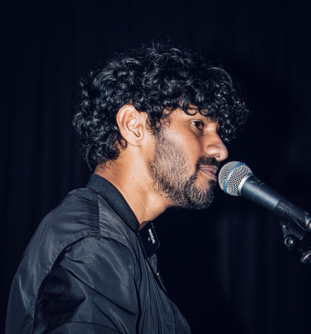 TAKEE singing into a microphone on stage